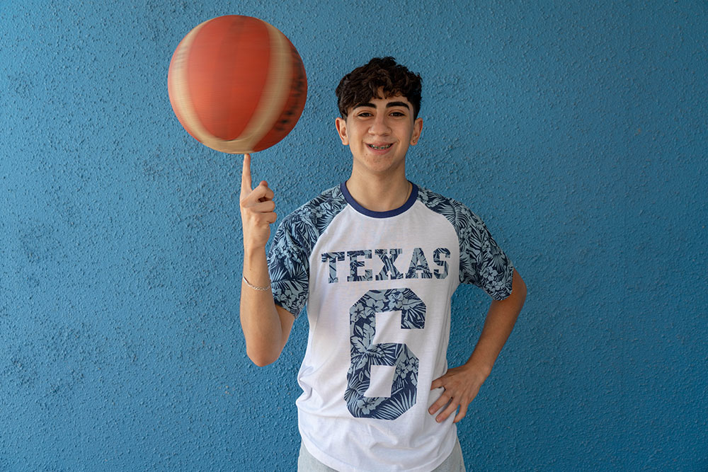 Maximiliano smiling and spinning a basketball